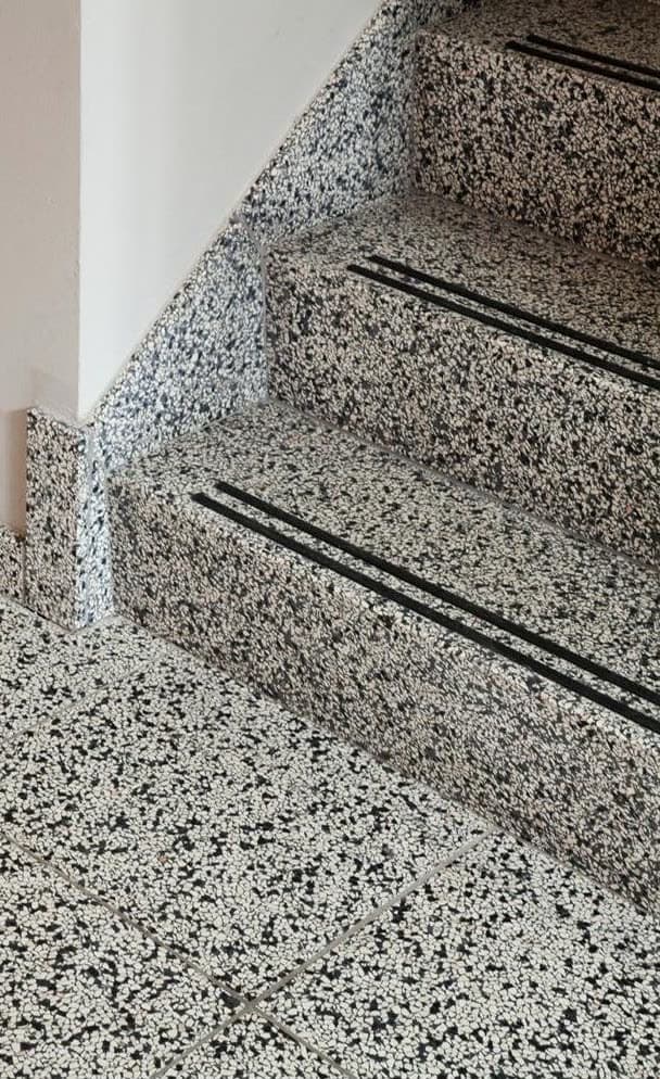 Escalier en granit moucheté noir et blanc, bandes antidérapantes incrustées dans la marche