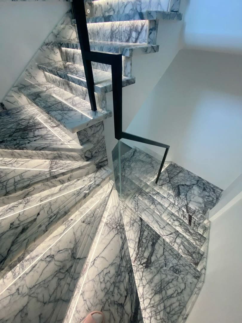 Escalier tournant en marbre clair aux veines sombres, vu depuis le palier