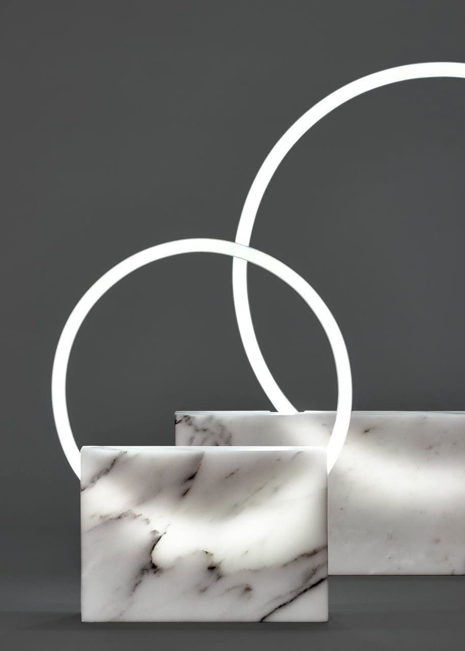 Lampes en anneau lumineux plantées dans un socle de marbre blanc