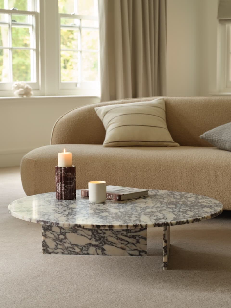 Table basse ovale en marbre veiné, piétement en croix dans la même pierre